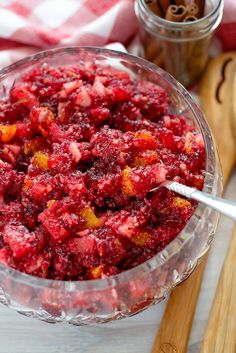 a glass bowl filled with cranberry sauce on top of a wooden cutting board