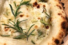 a close up of a pizza on a wooden surface with herbs sprinkled on it