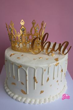 a white cake topped with a gold crown and the word boo spelled out in cursive writing