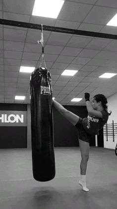 a woman kicking a punching bag in a gym