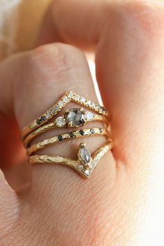 a woman's hand with three different rings on her finger and the other ring is gold