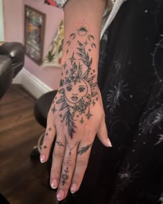 a woman's hand with a sun and moon tattoo on it