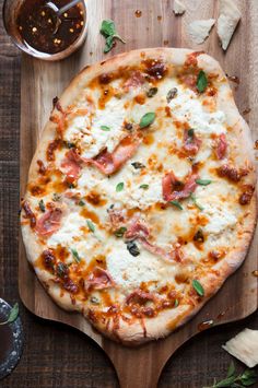 a pizza sitting on top of a wooden cutting board next to a bowl of sauce