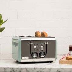 a toaster sitting on top of a counter next to a potted plant and some bread