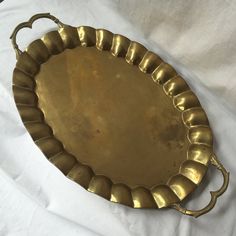 an antique brass tray with handles on a white sheet