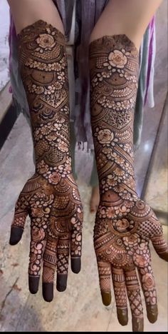 two hands with henna tattoos on them, one is showing off the intricate design