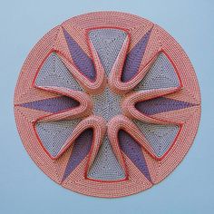 a circular object made out of woven material on top of a blue surface with an orange center