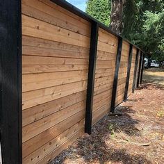 a row of wooden fence posts next to a tree