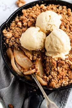 two scoops of ice cream are in a skillet with apples and walnuts