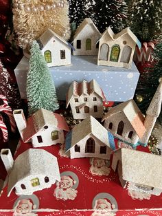 small houses and trees are on display in front of a christmas tree with snowflakes