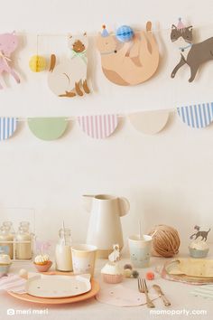 a table topped with plates and cups filled with cake next to cupcakes covered in frosting