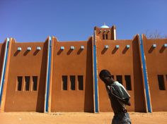 a man standing in front of a building with blue and white lines on the side