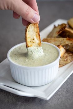 a person dipping some kind of food into a small white bowl on top of a plate