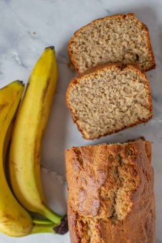 sliced banana bread next to two bananas on a table