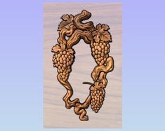 a wooden plaque with grapes and leaves in the shape of a letter c on a blue background