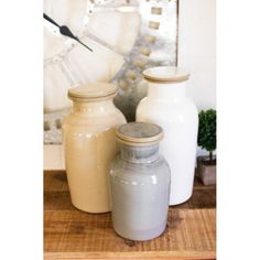 three white jars sitting on top of a wooden table