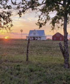 the sun is setting behind a farm house