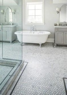 a white bath tub sitting under a window next to a sink and mirror in a bathroom