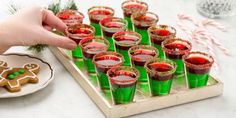 green glasses filled with red liquid and gingerbread cookies on a tray next to candy canes