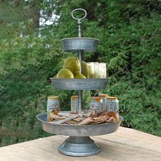 three tiered tray with apples and cheese on it sitting on top of a wooden table