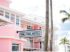 the pink hotel sign is in front of some palm trees and two balconies