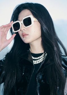 a woman with long black hair wearing white sunglasses