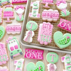 some decorated cookies are on a cooling rack and one is pink, green and white