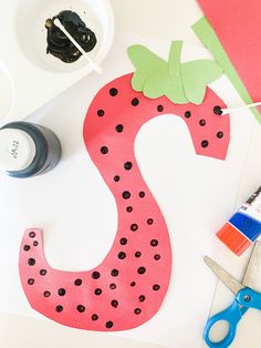 paper cut out of the shape of a letter s with scissors and glue next to it