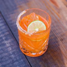 an orange drink with a slice of lime on the rim