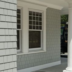 a black and white fire hydrant sitting in front of a gray brick building with two windows