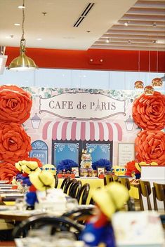 tables and chairs are set up in front of a cafe with red roses on the wall