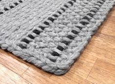 a gray and black rug sitting on top of a wooden floor