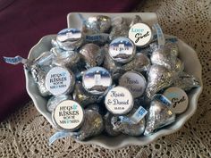 a white bowl filled with lots of silver foil wrapped hershey kisses on top of a table