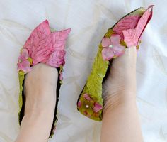 a woman's feet wearing pink and green shoes with flowers painted on the soles