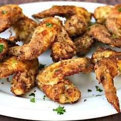 fried chicken wings on a white plate with parsley sprinkled around the edges