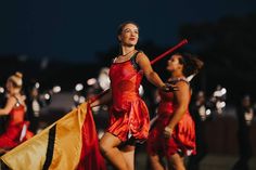 a group of women in red dresses holding flags