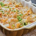 a casserole dish with peas and cheese in it sitting on a wooden table