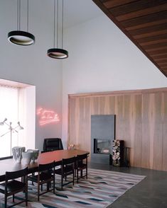 a dining table and chairs in a room with wood paneling on the wall behind it