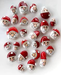 a bunch of santa claus painted rocks on a white table with red and white caps