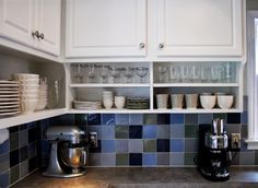 a kitchen with white cabinets and blue tile backsplash