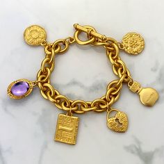 "Vintage 80s Gloria Vanderbilt Satin Matte Gold Plated Chain Link Charm Bracelet SIGNED. Beautiful Vintage 80s Gloria Vanderbilt Charm Bracelet. Gorgeous Satin Gold Plated Chain Link Charm Bracelet In Classic Signature Gloria Vanderbilt Style. Beautifully Crafted With Six Unique Double Sided Embossed Charms Except For The Purple Glass Cabochon. Charms Depict Two Flower Theme Medallions Shapes, One Heart Keyhole, One Book, One Perfume Bottle Stamped With Classic Gloria Vanderbilt Swan Logo With S Swan Logo, First Perfume, Gloria Vanderbilt, Purple Glass, Gold Plated Chains, Matte Gold, Chain Link, Perfume Bottles, Gold Plate