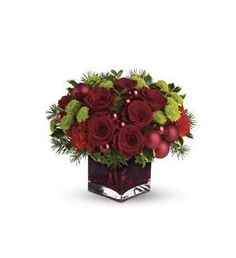 a christmas bouquet with red roses and greenery in a square glass vase on a white background