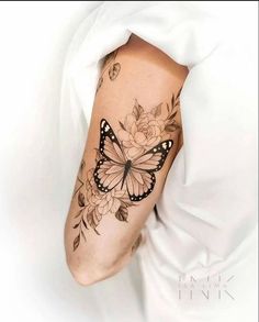 a woman's arm with a butterfly and flowers tattoo on the left side of her body