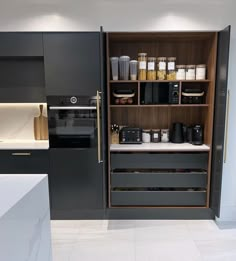 an open cabinet in the middle of a kitchen filled with appliances and food storage items