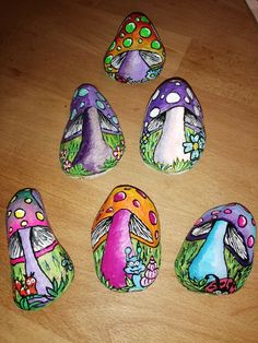 four painted rocks sitting on top of a wooden table