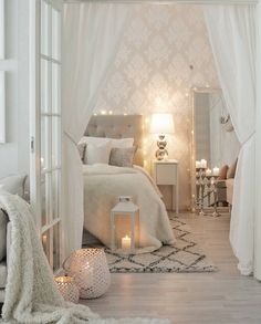 a bedroom with white curtains and lights on the ceiling