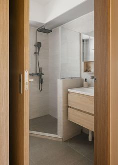 an open door leading to a bathroom with a sink, shower and mirror in it