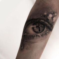 an eye with a cross on it is shown in the middle of this forearm tattoo