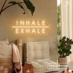 a neon sign that reads inhale exhale next to a chair and table with candles on it