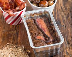 some food is sitting on a table next to bread and other foods are in plastic containers